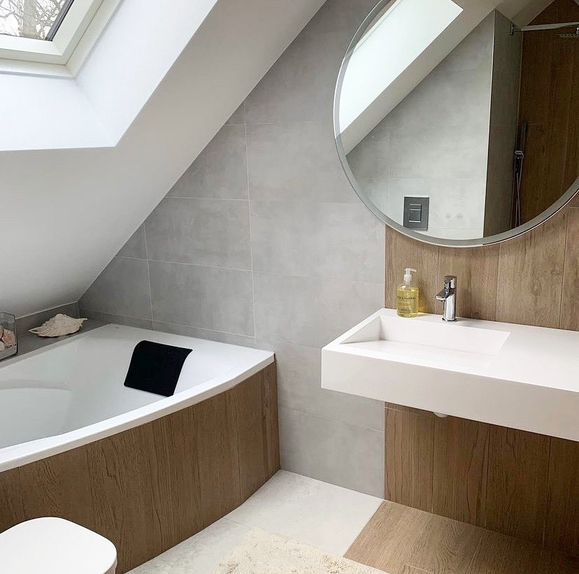 Space-saving loft bathroom with corner bath under eaves